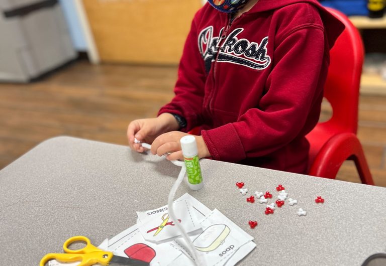 ocoee oaks preschool child making a bracelet and cutting paper