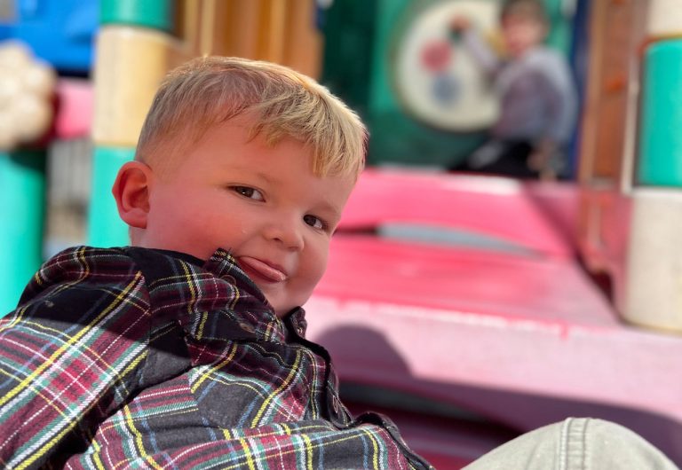 ocoee oaks preschool little boy smiling with tongue out on playground set