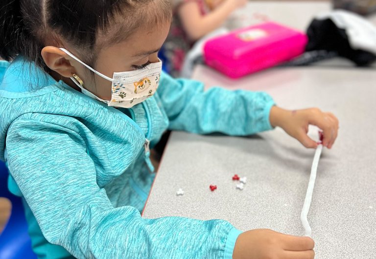 ocoee oaks preschool little girl making a bracelet
