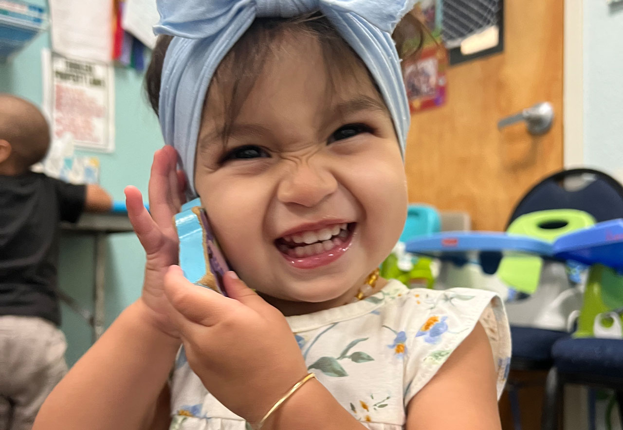 ocoee oaks preschool little girl smiling and holding a toy up to her face